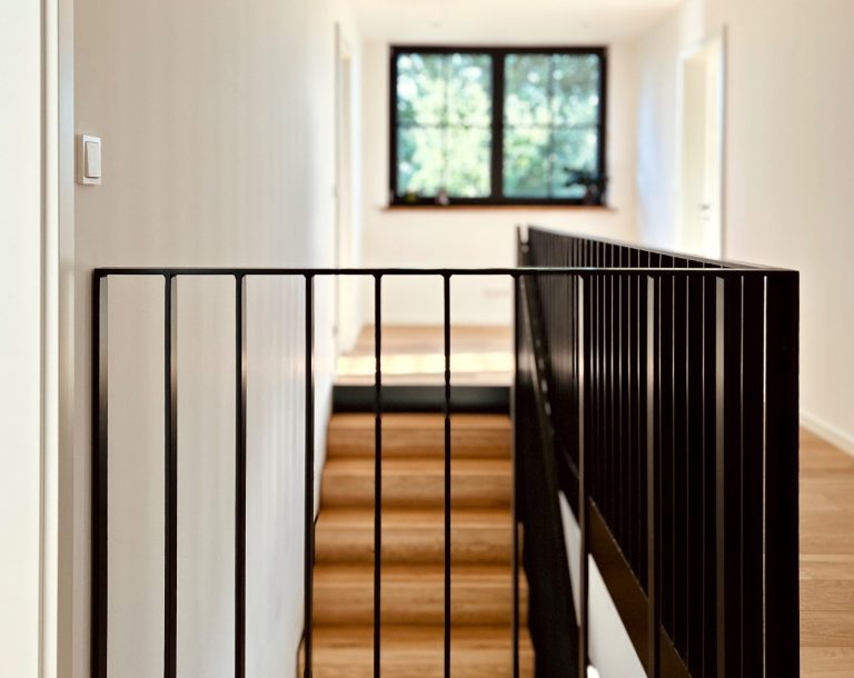Treppengeländer Galerie Blick auf Galerie mit schwarzem Metallgeländer und Holzstufen im Obergeschoss