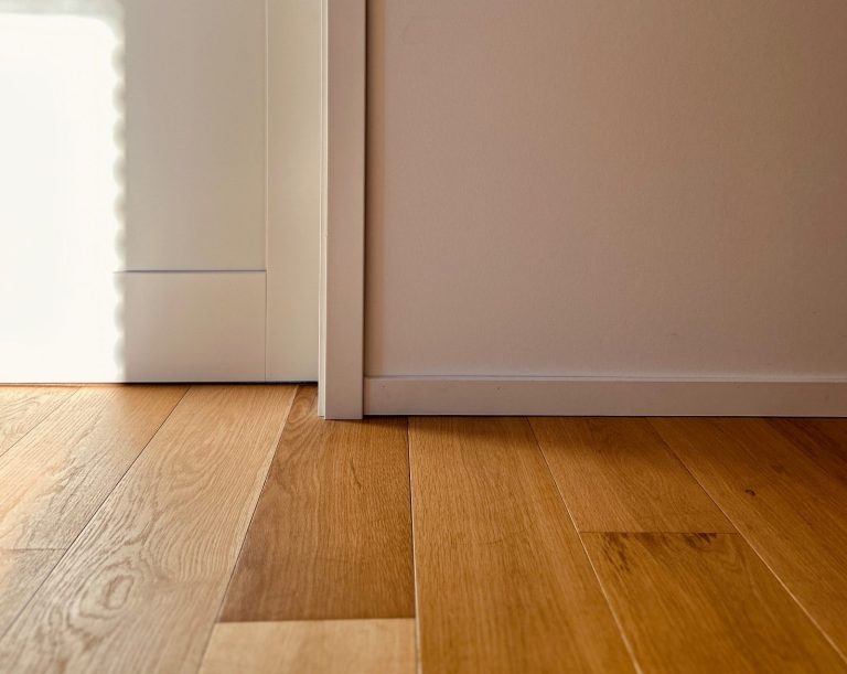 Parkettboden Holzdetail Detail eines hellen Parkettbodens mit Sockelleiste und Wandanschluss im Innenraum